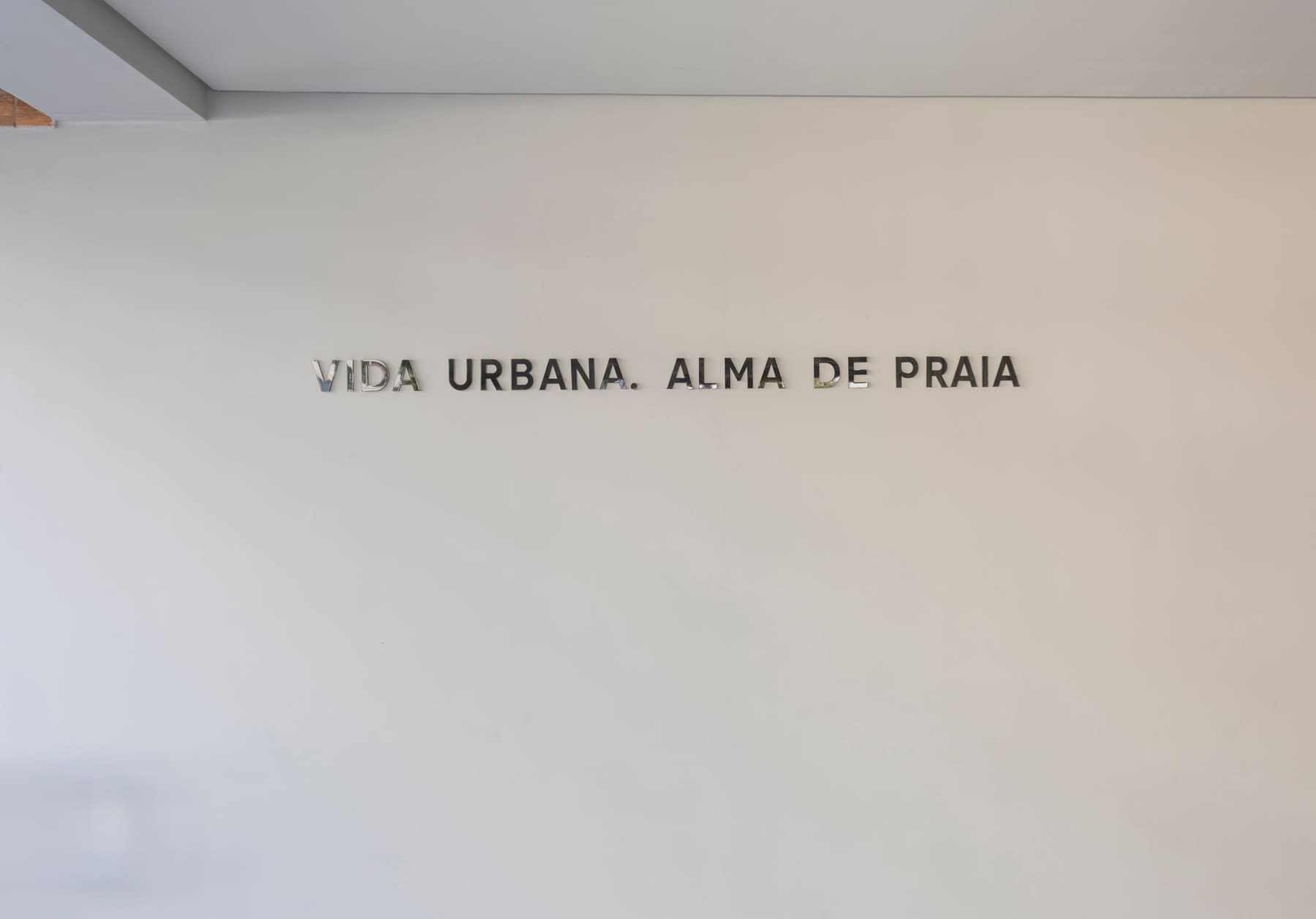 Assinatura 'Vida urbana. Alma de praia' aplicada na parede
